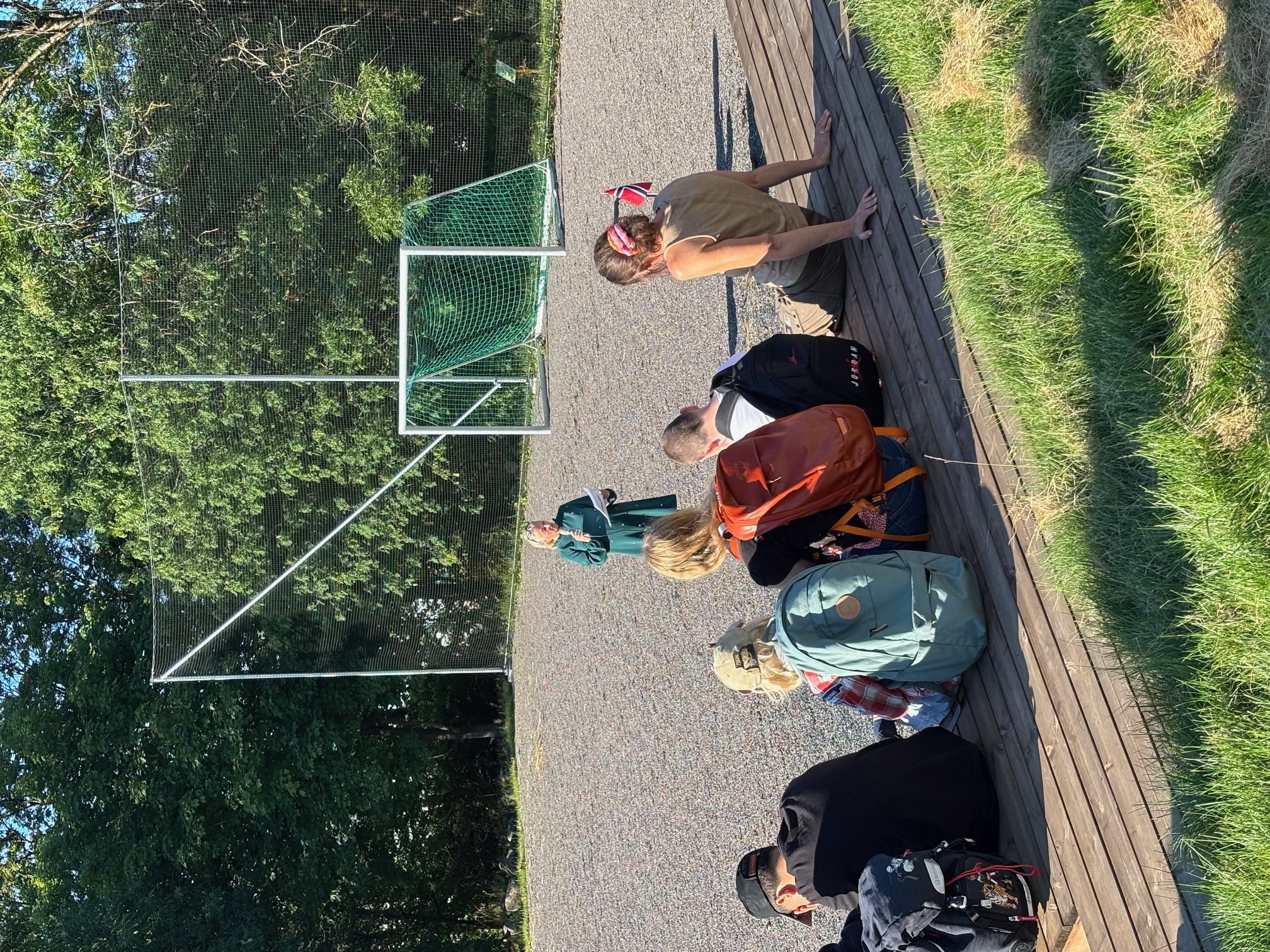 en gruppe mennesker som sitter på en benk foran et fotballmål